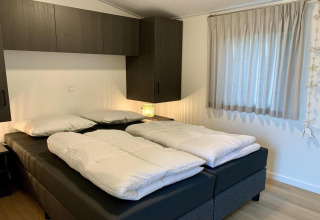 Camera da letto in uno chalet accogliente nei Paesi Bassi con letti singoli, mobili moderni e tende chiare.
