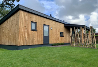 Buitenaanzicht van Pleasant chalet met veranda, modern houten huisje met groene tuin in Nederland.