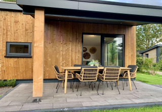 Chalet moderno con veranda coperta, tavolo da pranzo e sedie all’aperto nei Paesi Bassi.