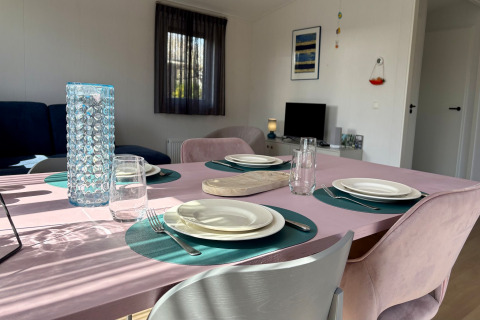 Mesa de comedor puesta con platos y vasos en un chalet soleado cerca de la playa de Sint Maartenszee, Holanda.