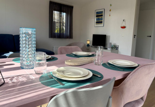 Spisebord dækket med service og glas i en solrig chalet tæt på Sint Maartenszee Strand, Holland.