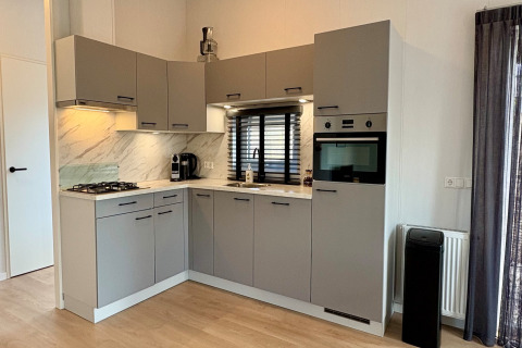 Moderne grijze keuken in een chalet dicht bij Sint Maartenszee Beach, Nederland, met marmeren accenten.