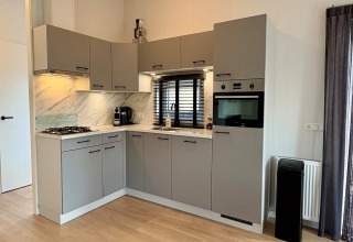 Cocina gris moderna en un chalet cerca de Sint Maartenszee Beach, Países Bajos, con electrodomésticos integrados.