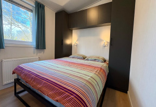 Chambre avec lit double et draps colorés dans un chalet près de la plage de Sint Maartenszee, Pays-Bas.