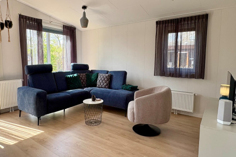 Moderne woonkamer in chalet nabij Sint Maartenszee strand, Nederland, met blauwe zetel en stoel.