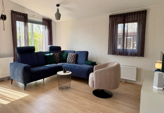 Sala moderna en un chalet cerca de la playa Sint Maartenszee, Países Bajos, con sofá azul y sillón beige.