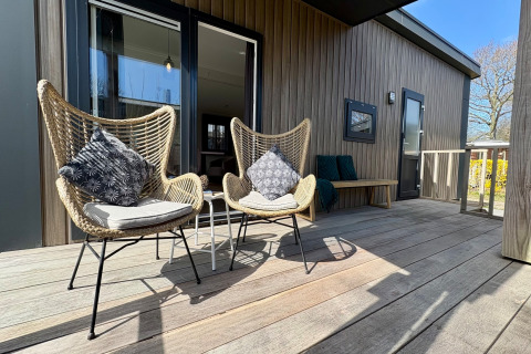 Solrig veranda ved Chalet nær Sint Maartenszee Strand i Holland, med komfortable stole og puder.
