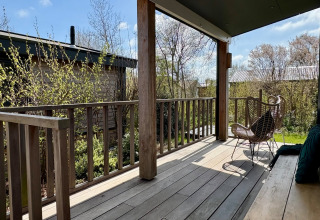 Veranda in legno con sedia e panca al Chalet vicino a Sint Maartenszee Beach, Paesi Bassi, in primavera.