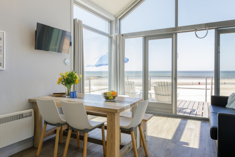 Soggiorno di una casa sulla spiaggia al Resort Beach Houses Julianadorp 1 con vista mare e tavolo da pranzo, Olanda.