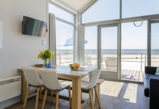 Soggiorno di una casa sulla spiaggia al Resort Beach Houses Julianadorp 1 con vista mare e tavolo da pranzo, Olanda.