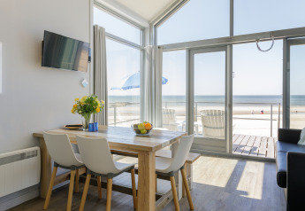 Woonkamer in een strandhuis van Resort Beach Houses Julianadorp 1 met eettafel en zeezicht, Nederland.
