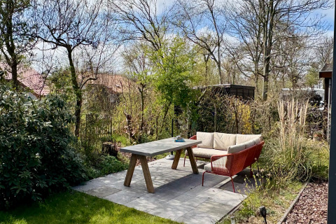 Zona patio con divano e tavolo in giardino verde presso Chalet vicino alla spiaggia Sint Maartenszee, Olanda.