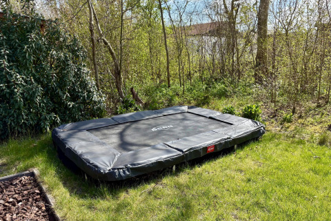 Bodengleiches rechteckiges Trampolin im Garten eines Chalets nahe Sint Maartenszee Strand, Niederlande.