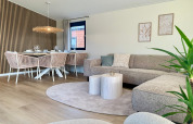 Modern eingerichtetes Wohnzimmer im Chalet am Strand mit Essbereich, Sofa, Pflanzen und Holzelementen.