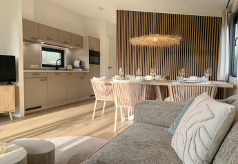 Modernes Wohnzimmer und Küche in einem Strandhaus bei Sint Maartenszee mit stilvollem Essbereich und Holzwand.