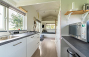 Cuisine moderne et lumineuse dans une tiny house aux Pays-Bas avec grandes fenêtres et coin salon.