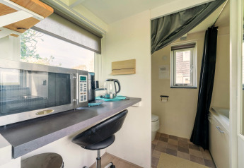 Compacte keukenhoek met microgolfoven en waterkoker in tiny house in Nederland, zicht op de badkamer.