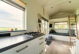 Licht en modern interieur van een tiny house in Nederland met keuken, zithoek en mezzanine.