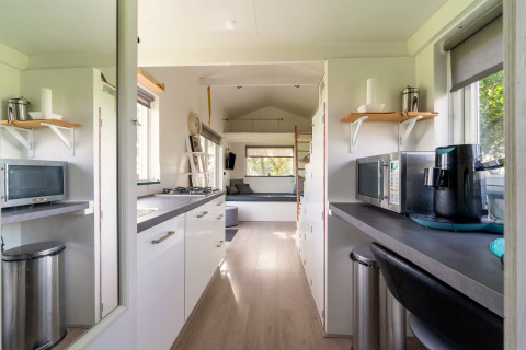 Licht en gezellig tiny house-interieur met keuken en zitruimte in Nederland, van binnenuit gezien.