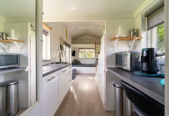 Licht en gezellig tiny house-interieur met keuken en zitruimte in Nederland, van binnenuit gezien.