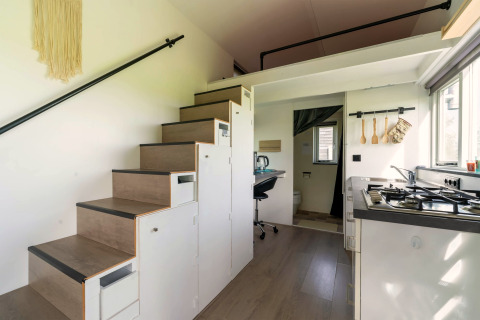 Moderne tiny house in Nederland met keuken, opbergtrap, werkplek en efficiënte ruimte-indeling.