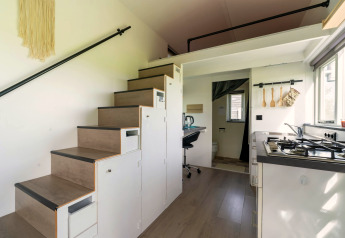Moderne tiny house in Nederland met keuken, opbergtrap, werkplek en efficiënte ruimte-indeling.