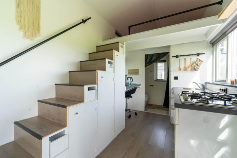 Interior moderno de tiny house en los Países Bajos con cocina, escaleras de almacenaje y espacio de trabajo.
