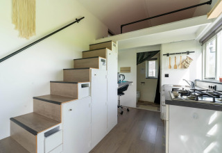 Interior moderno de tiny house en los Países Bajos con cocina, escaleras de almacenaje y espacio de trabajo.