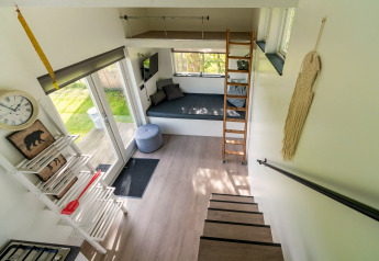 Licht en modern interieurtje van een tiny house in Nederland met trap, slaaploft en gezellige zithoek.