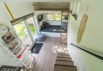 Intérieur d'une tiny house lumineuse et moderne aux Pays-Bas avec mezzanine, escalier et espace détente agréable.