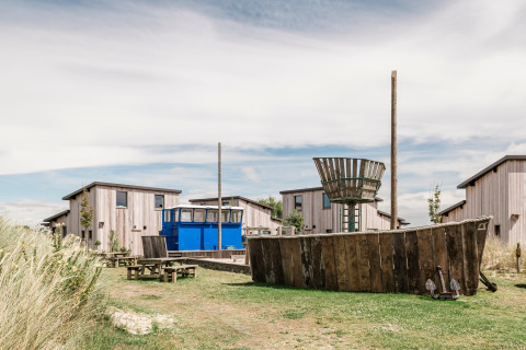 Lodges in legno e area giochi con barca al Juttershut Duynpark, Callantsoog, Paesi Bassi in una giornata serena.