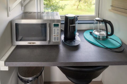 Keukenblad in tiny house in Nederland met microgolf, koffiemachine en elektrische waterkoker.