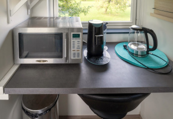 Keukenblad in tiny house in Nederland met microgolf, koffiemachine en elektrische waterkoker.