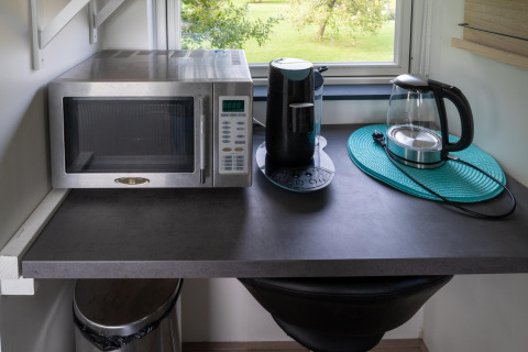 Encimera de cocina en tiny house de Países Bajos con microondas, cafetera y hervidor eléctrico.