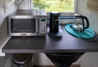 Encimera de cocina en tiny house de Países Bajos con microondas, cafetera y hervidor eléctrico.