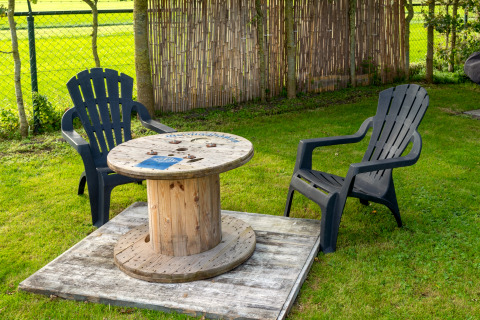 Buiten zitje met twee zwarte stoelen en een kabelspoel tafel bij Tiny House in Nederland.