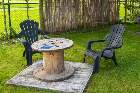 Zona de asientos al aire libre con dos sillas negras y una mesa de bobina en Tiny House, Países Bajos.