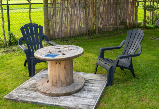 Zona de asientos al aire libre con dos sillas negras y una mesa de bobina en Tiny House, Países Bajos.