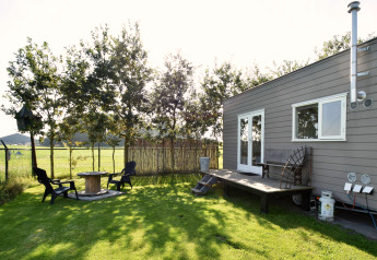 Kleine woning met terras en tuin, zitplaats in de zon, gelegen in een weide in Nederland.