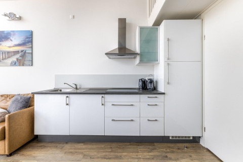 Cucina moderna al Resort Beach Houses Julianadorp 1, Paesi Bassi, con mobili bianchi e pavimento in legno.