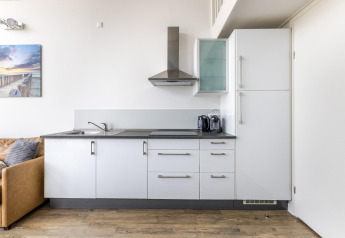 Moderne keuken in Resort Beach Houses Julianadorp 1, Nederland, met witte kasten en houten vloer.