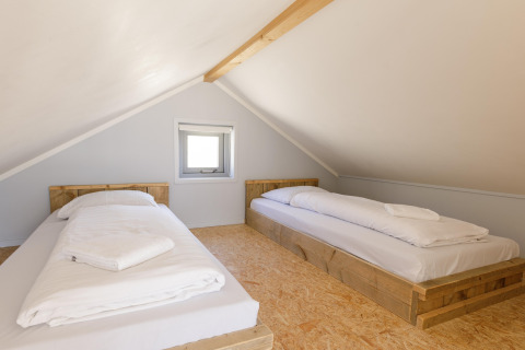 Camera mansardata con due letti singoli su strutture in legno al Beach Houses Julianadorp, Paesi Bassi.