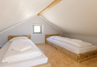 Camera mansardata con due letti singoli su strutture in legno al Beach Houses Julianadorp, Paesi Bassi.