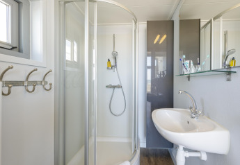 Lichte, moderne badkamer met glazen douche en wastafel in een strandhuis in Julianadorp, Nederland.