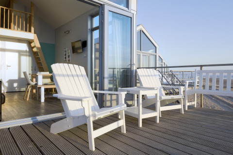 Casa sulla spiaggia con terrazza, due sedie bianche e vista mare a Julianadorp, Paesi Bassi.