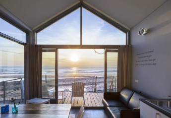 Interieur van een strandhuis bij Resort Beach Houses Julianadorp 1 in Nederland met zonsondergang boven zee.