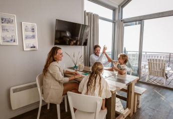 Gezin samen aan tafel in een strandhuis bij Resort Beach Houses Julianadorp in Nederland.