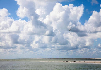 Uitgestrekte lucht met wolken en kalme zee aan het strand bij Resort ‘Beach Houses Julianadorp 1’ in Nederland.