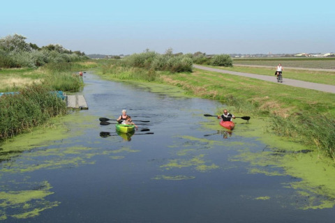 Due persone in kayak remano in un canale stretto vicino al Resort Beach Houses Julianadorp in Olanda.