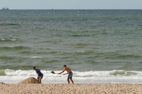 Due persone scavano nella sabbia sulla spiaggia vicino al mare presso il Resort Beach Houses Julianadorp 1, Paesi Bassi.